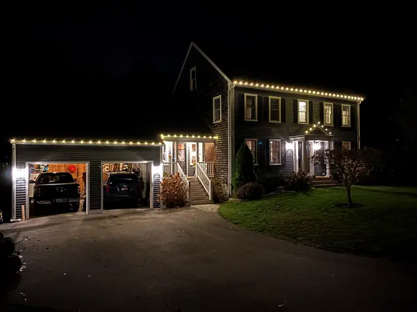 Warm white roofline lighting on a home in Scituate, MA