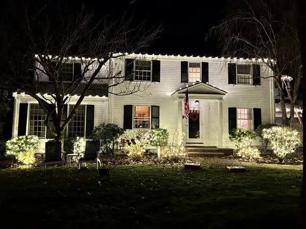 Warm white roofline lighting on a home in Wellesley, MA